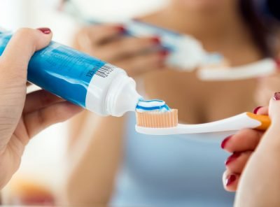 Portrait of pretty young woman brushing her teeth in the bathroom.